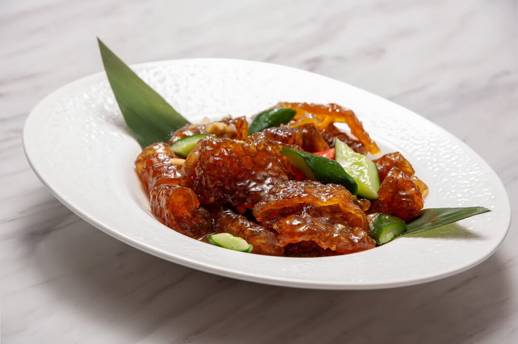 「順德嗆魚皮」(280元),廣東順德經典涼菜,主廚汆燙後冰鎮魚皮,保留Q彈脆口質地,拌入香蔥、芫荽與芥末香醋,酸香微辣開胃,展現順德菜「鮮、爽、滑」的風味精髓,開胃又解膩。圖 / 台北凱撒大飯店提供