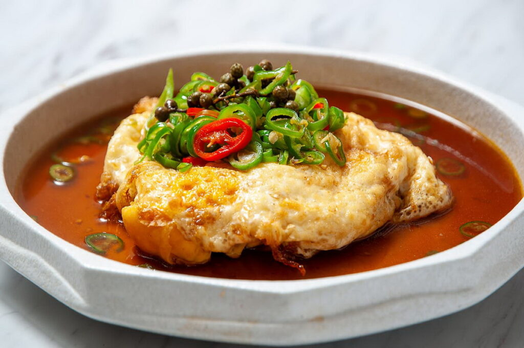 「藤椒炸蛋」(左,360元),融合麻香與酥脆的創意川菜,延續了川菜靈魂的麻香風味,外層酥脆、內餡流心,搭配新鮮青藤椒醬汁,香麻不嗆、餘韻悠長。圖 / 台北凱撒大飯店提供