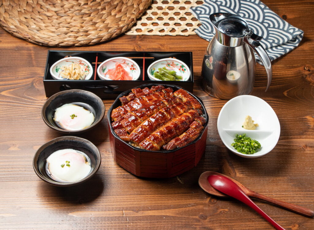 雙人夢幻鰻魚桶飯3+1吃|售價 $888 元,來四種不同品味體驗:原味吃法完美呈現炭火烤鰻的鹹香濃郁;加入蔥花與芥末後,帶出清爽辛香的口感層次;淋上溫泉蛋則增添滑順濃香又細膩的口感,提升整體香氣;最後一吃淋上高湯,化身日式茶泡飯,滋味清爽且回甘