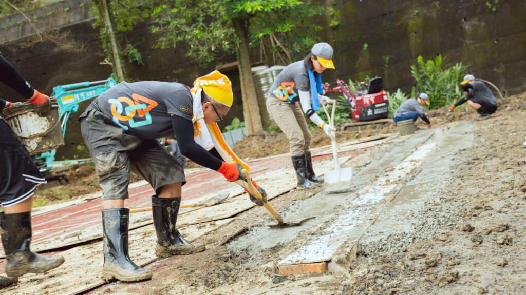 遠雄志工在跑道旁挖出導流積水的排水溝，再灌漿、鋪面整平。(圖遠雄文教公益基金會提供)