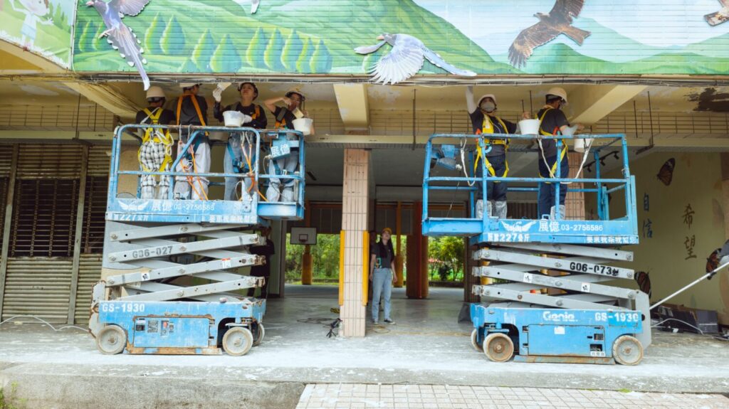 透過高空作業車，遠雄志工針對走廊天花板塗刷防水漆。(圖/遠雄文教公益基金會提供)