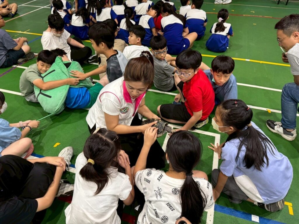 洪婉臻市議員帶著「雪中紅」,向學童們介紹紅腿象龜的特色。(圖/遠雄文教公益基金會提供)