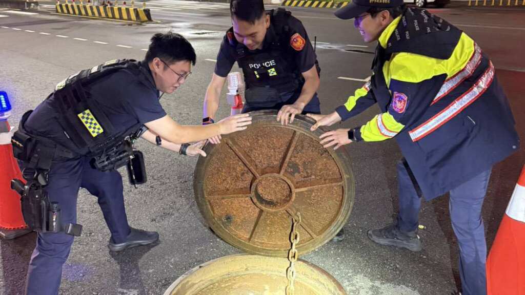 ▲颱風天人孔蓋離家出走,中市3警合力扛百公斤才復位。(台中警方提供)