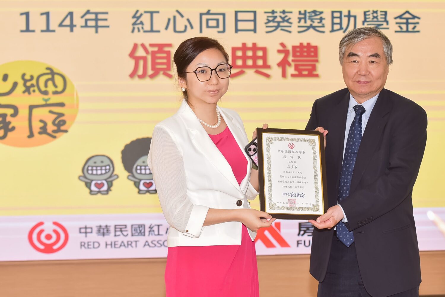 紅心字會理事長劉緒倫(右)頒贈感謝狀給房產顧問「房多多」團隊代表高沛琦，捐助獎助學金。(圖/紅心字會 提供)