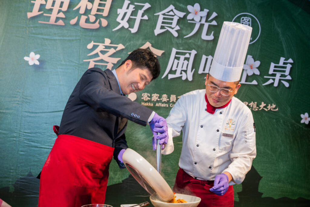 彭俊傑主廚現場指導邱星崴副主委創作哈客小炒義大利麵。(圖/業者提供)