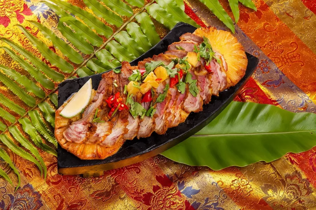 「薑黃烤豬頸肉」選用油花分布均勻、彈嫩多汁的豬頸肉,佐以南洋風味的薑黃香料醃製,慢火炙烤,表皮微焦、肉香誘人。/台北凱撒大飯店提供