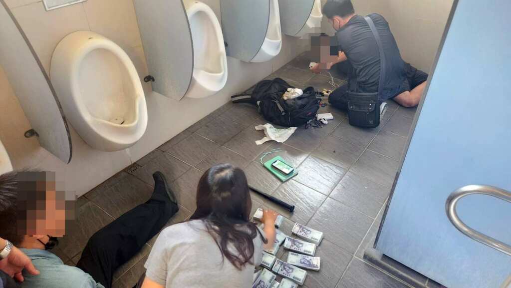 ▲員林警埋伏查緝，一名員警因尿急進入公廁，竟意外發現47歲張姓男子（車手）與25歲顏姓男子（收水手）在廁所行跡可疑，隨即通知同仁合力將兩人查獲，並當場查扣現金110萬元及3支手機。（彰化警方提供）