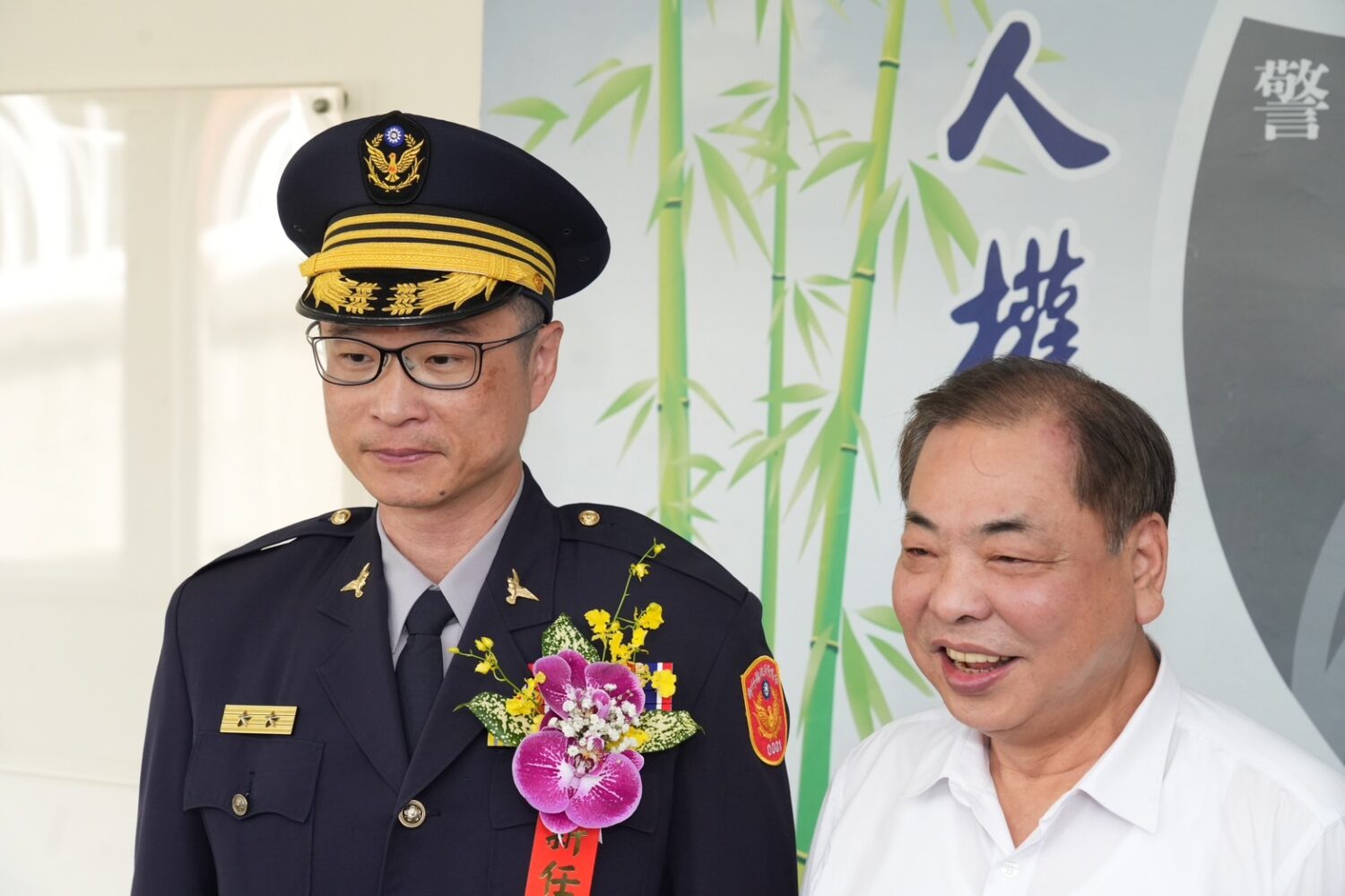 新竹縣政府警察局新任局長林建隆(左)於交接典禮中佩戴鮮花胸章,正式上任,副縣長陳見賢(右)親自出席表達歡迎之意。(圖/記者張家燁翻攝)