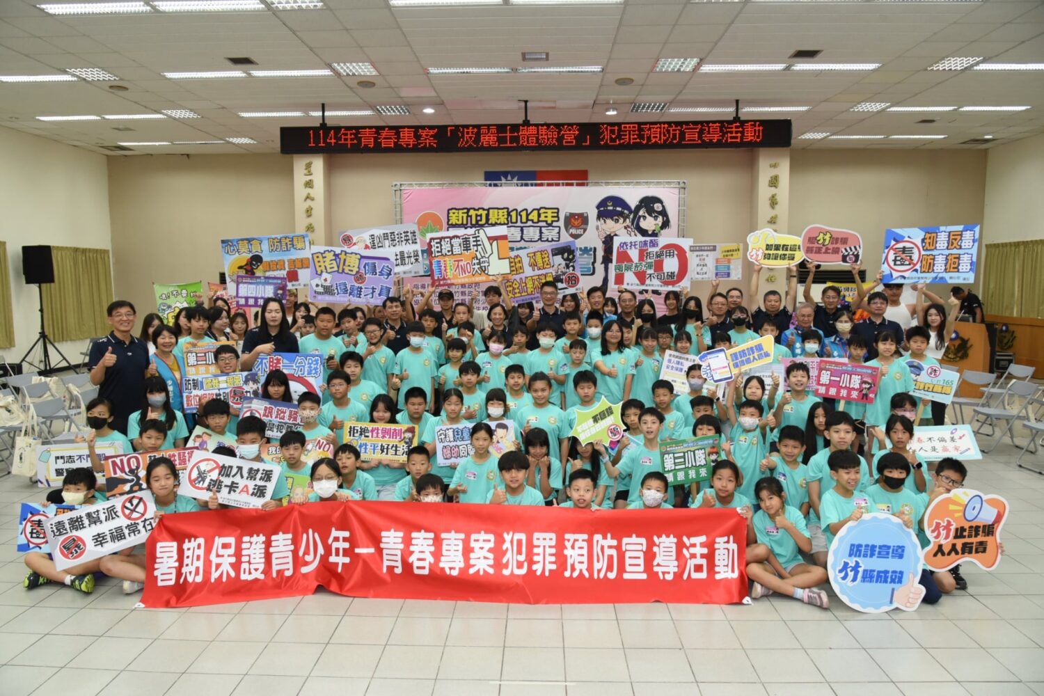 「波麗士體驗營」宣導活動的大合照,學生高舉防詐、反毒、拒絕性暴力等標語,展現守法決心。(圖/記者張家燁翻攝)