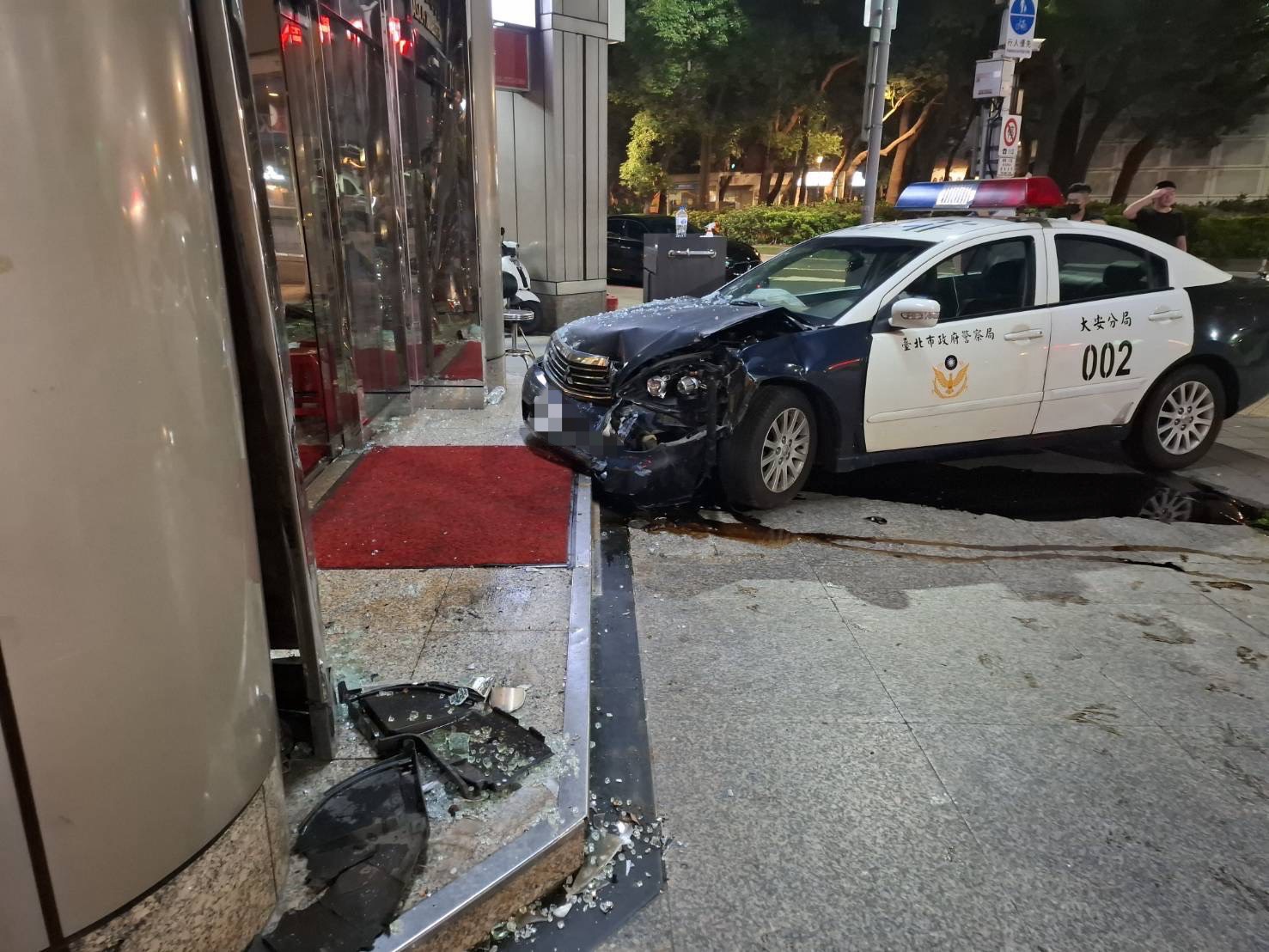 ▲警車車頭嚴重毀損,大樓的門柱及玻璃門也因此破裂。(翻攝畫面)