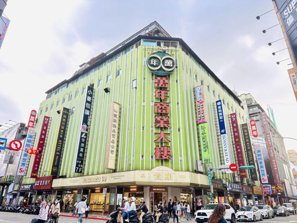 萬年商業大樓坐落於西門町鬧區三角窗地段，以綠色馬賽克磁磚與紅色霓虹招牌為標誌性造型，至今每晚燈火通明。(圖/風傳媒拍攝)