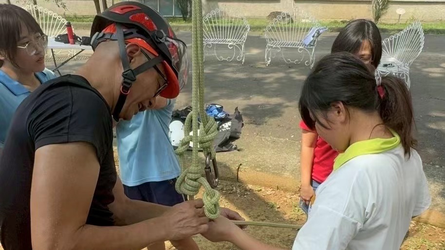 ▲崇仁專業教練李崑璋老師協助孩子學習繩索結法,為攀樹挑戰做好準備。