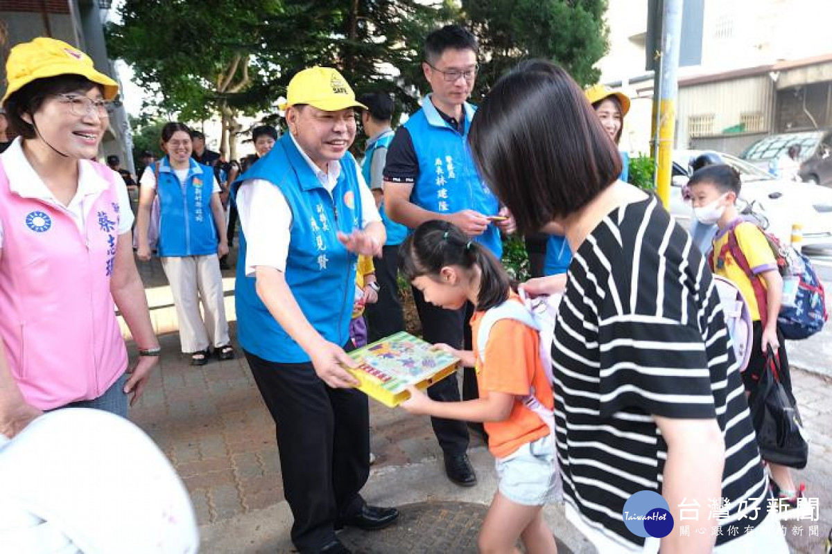副縣長陳見賢配戴小黃帽，在竹北市六家國小門口向學生發送交通安全小禮物。