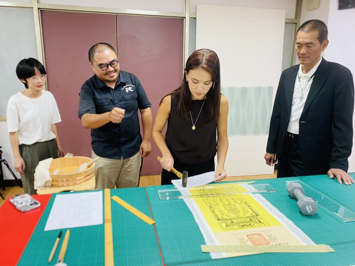 ▲修復師侯宗延指導Anaïs完成一幅「天上聖母大符」的手工卷軸。(記者蘇峯毅攝)