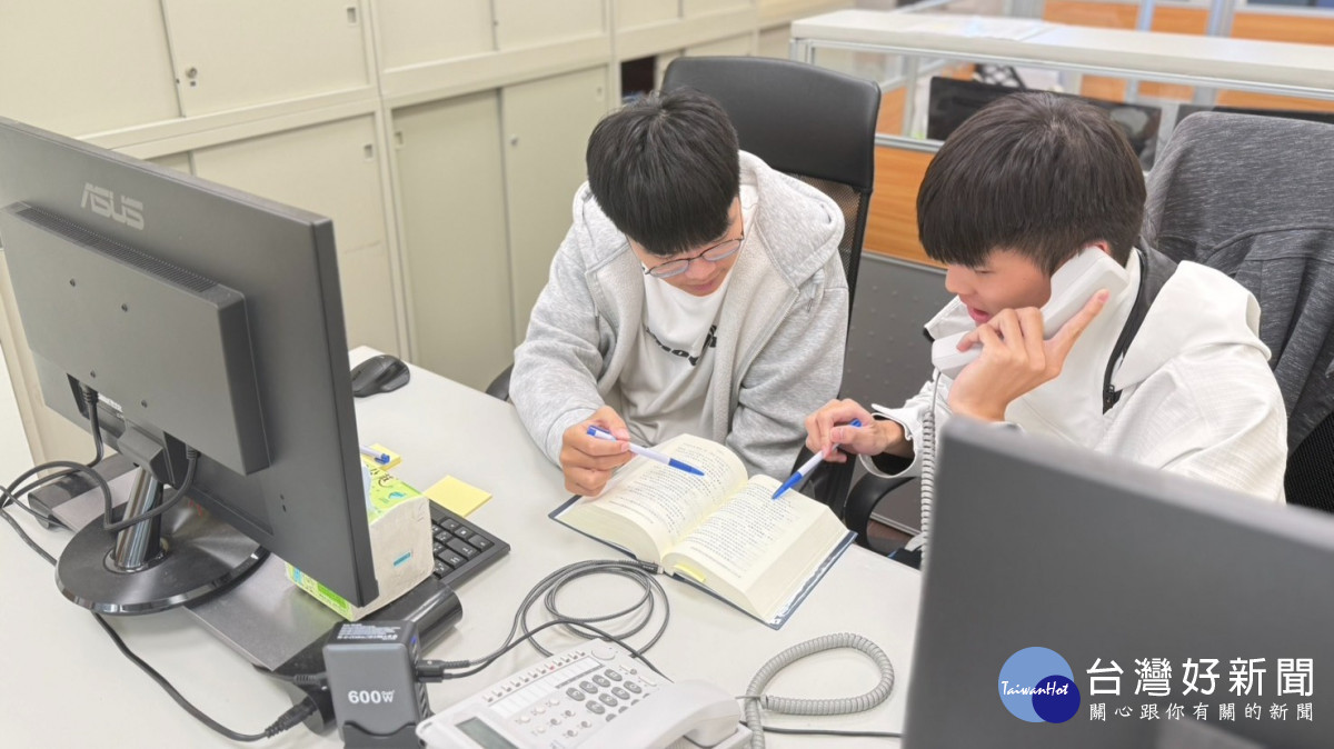 暑期工讀生劉向宏與孫勖宸接聽諮詢電話，翻閱書籍討論。