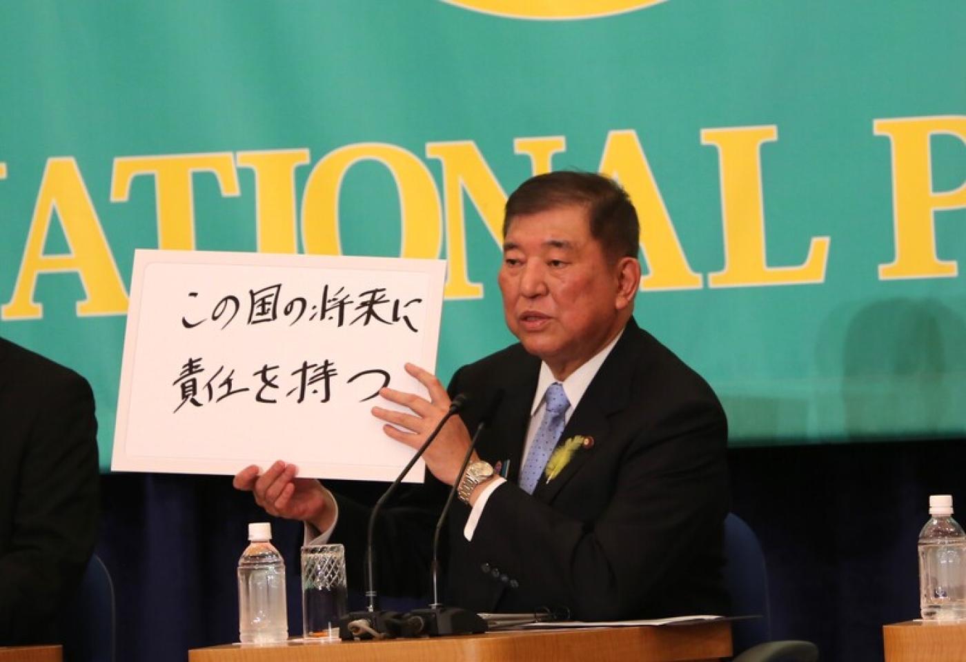 石破茂與公明黨的執政聯盟在7月眾議院失去過半多數後,他舉出寫著「要為這國家的將來負責」的政見牌,堅持續任首相。中央社