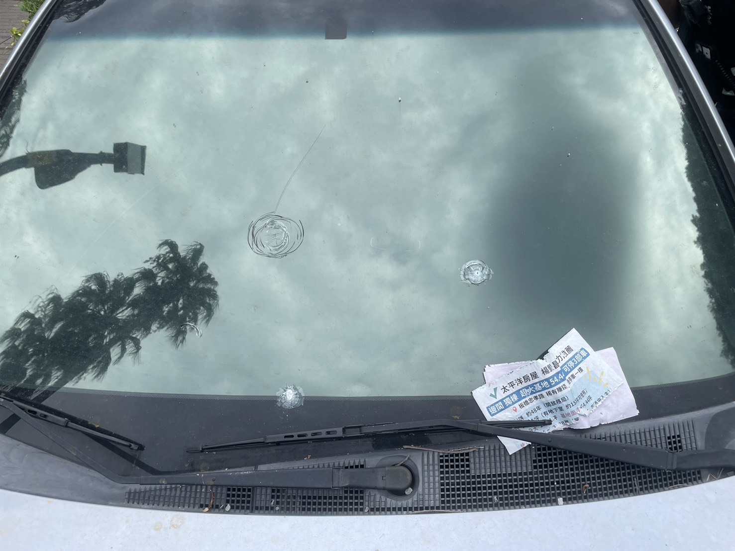 1輛停放在學校附近的銀色轎車,車身和玻璃佈滿了多處彈孔。