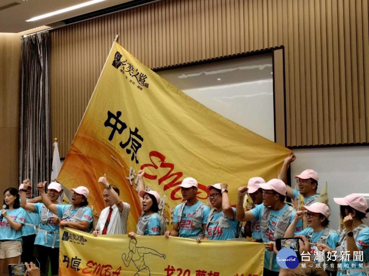 中原EMBA成員高舉隊旗,象徵群體合作與生命連結的教育實踐。