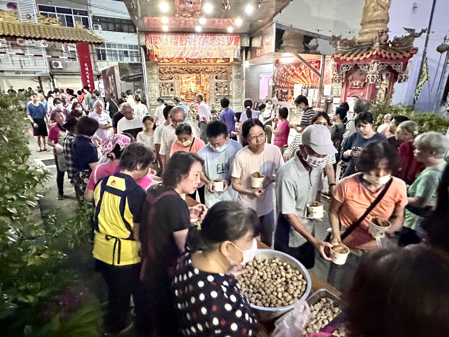 里民排隊領取社區志工準備的熱食，現場洋溢團圓氛圍。（圖/記者林照東攝）