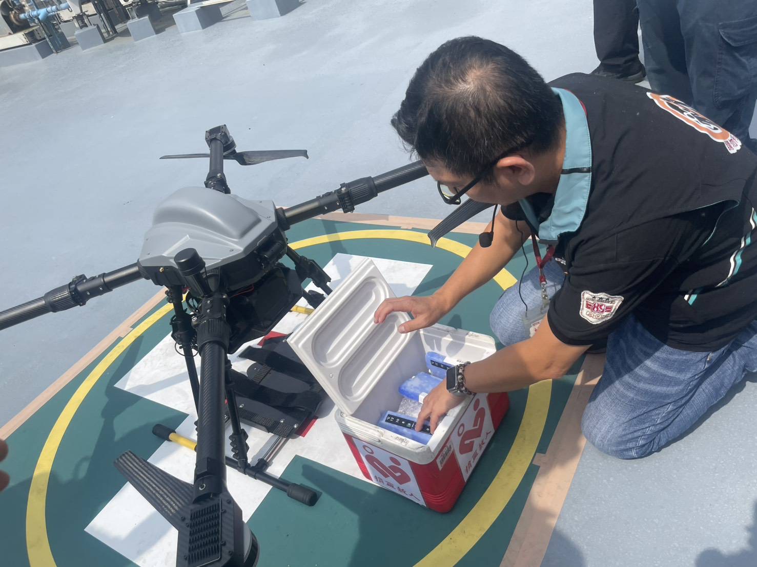 新竹捐血中心工作人員將血液放入專業運輸容器,搭載於無人機進行緊急送血展演,確保血液品質安全穩定。(圖/記者張家燁翻攝)