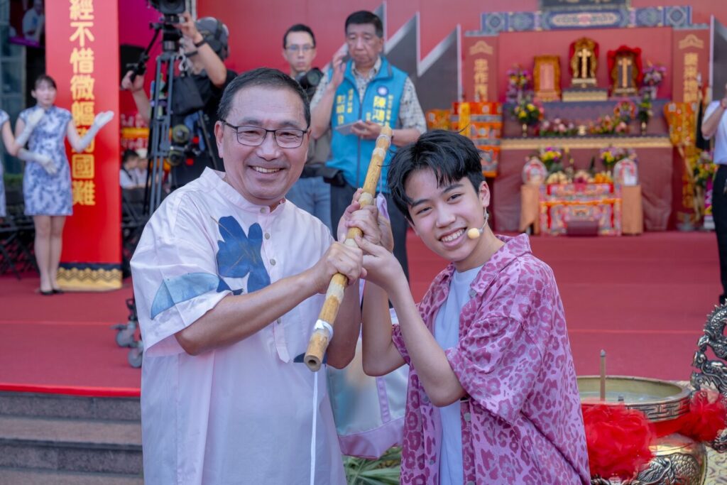 新北市市長侯友宜與JHall主唱子濬交接擔頭代表客家文化代代相傳、生生不息的精神。(圖/新北市客家事務局 提供)