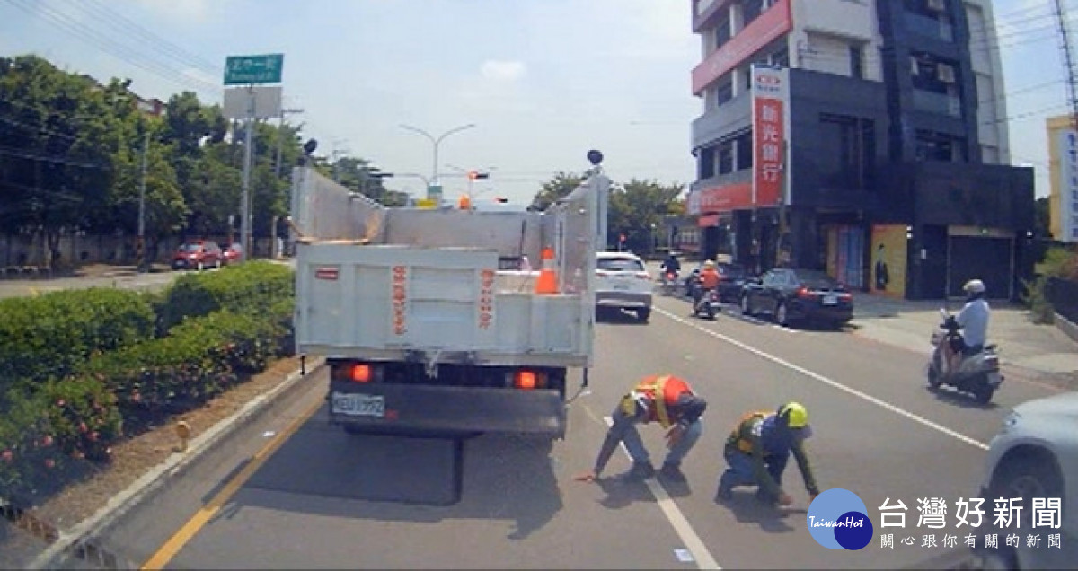 清潔隊員在車陣中撿拾民眾掉落之千元大鈔