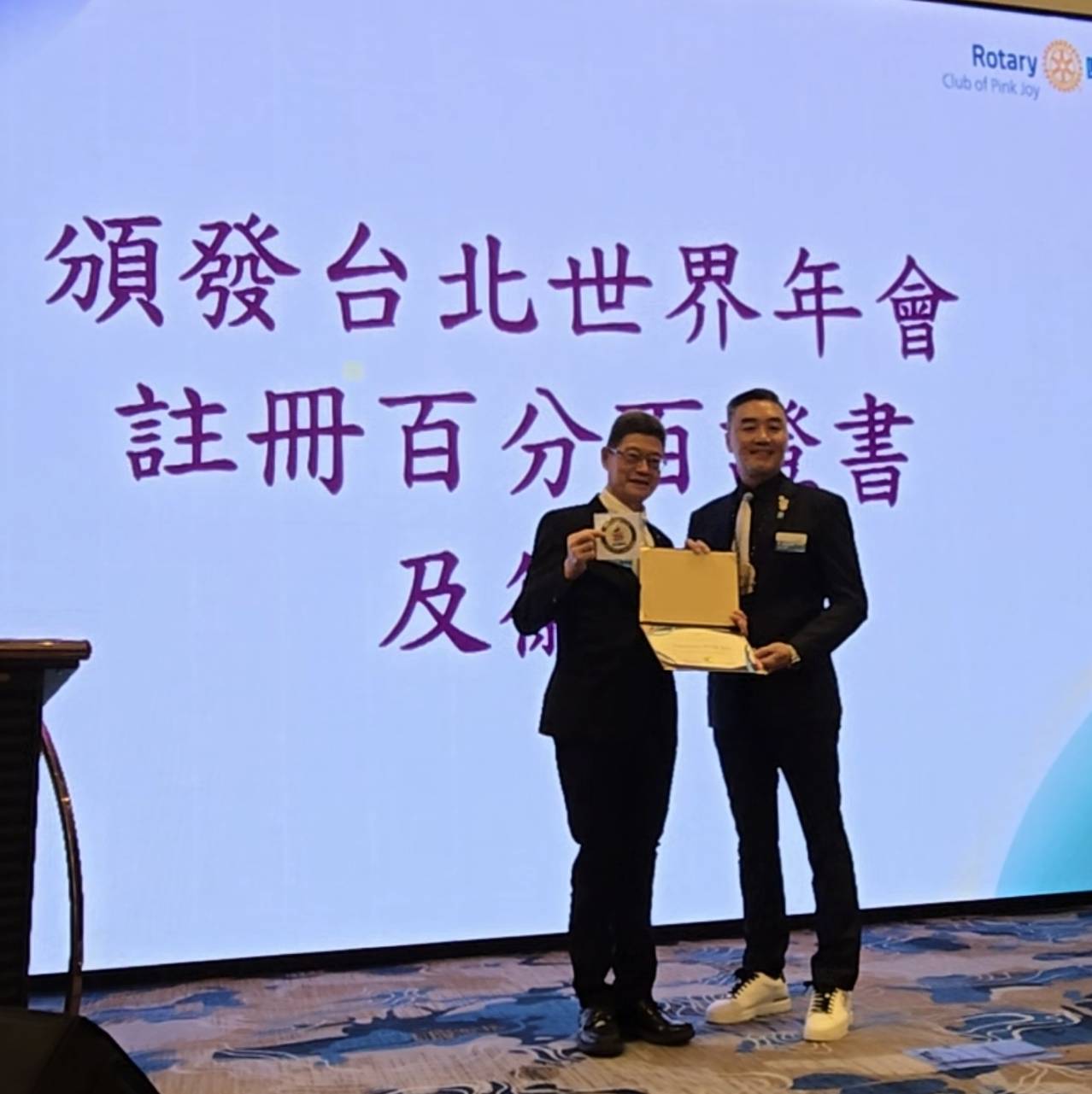 3502地區總監張玉斌(DG Daniel)頒發台北世界年會註冊百分百證書及徽章于社長張智淵。(記者 趙靜姸攝)