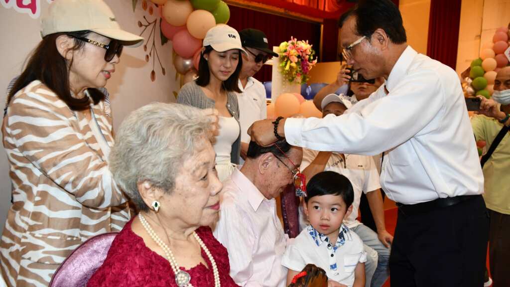 ▲林世賢市長為白金婚夫婦戴上金鎖片恭賀。（記者林明佑翻攝）