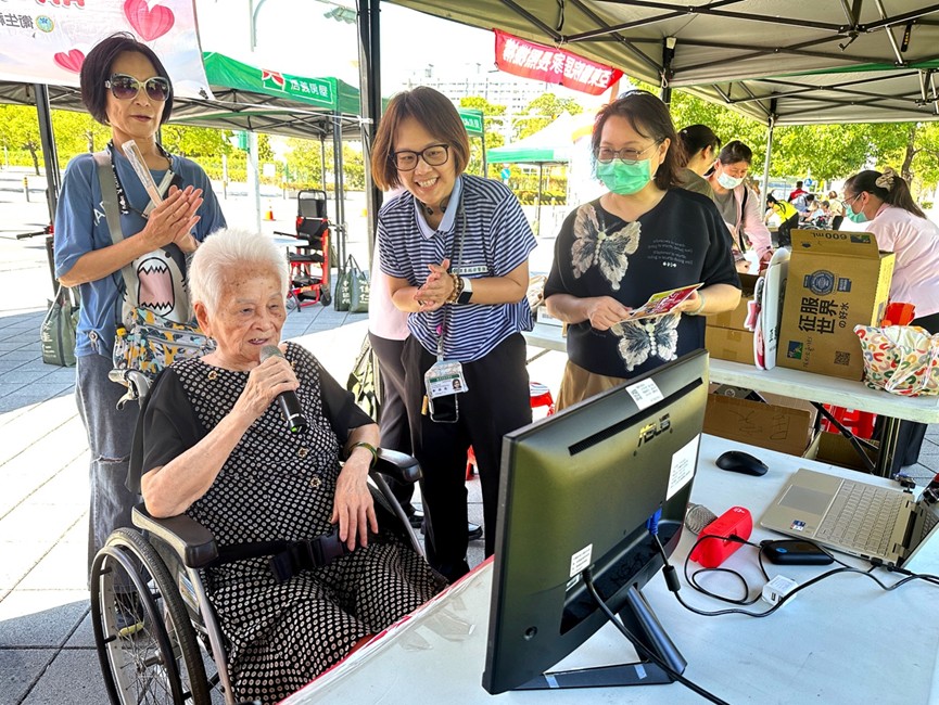 95歲的翁奶奶(左前)在卡拉OK攤位開心高歌,氣氛溫馨歡樂。(圖/北台灣無障礙運輸產業工會 提供)