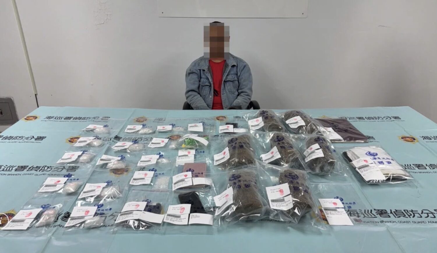 遭查獲的印尼籍逃逸移工「木奇」被帶回偵訊,桌面上陳列查扣的安非他命與大麻等證物,總重超過2公斤,全案依《毒品危害防制條例》移送橋頭地檢署偵辦。(圖/海巡署提供)