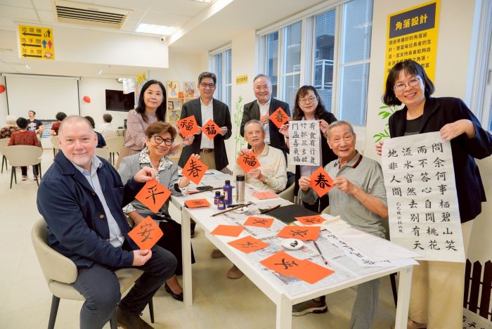 參訪「銀色知悠生」 美國學者肯定新北長者照護新模式 16 《圖說》體驗書法活動後,Rick博士(左1)、譚孟春教授(左2)與社會局專門委員林秀穗(右3)等人手拿紅宣紙及書法作品合影留念。〈社會局提供〉