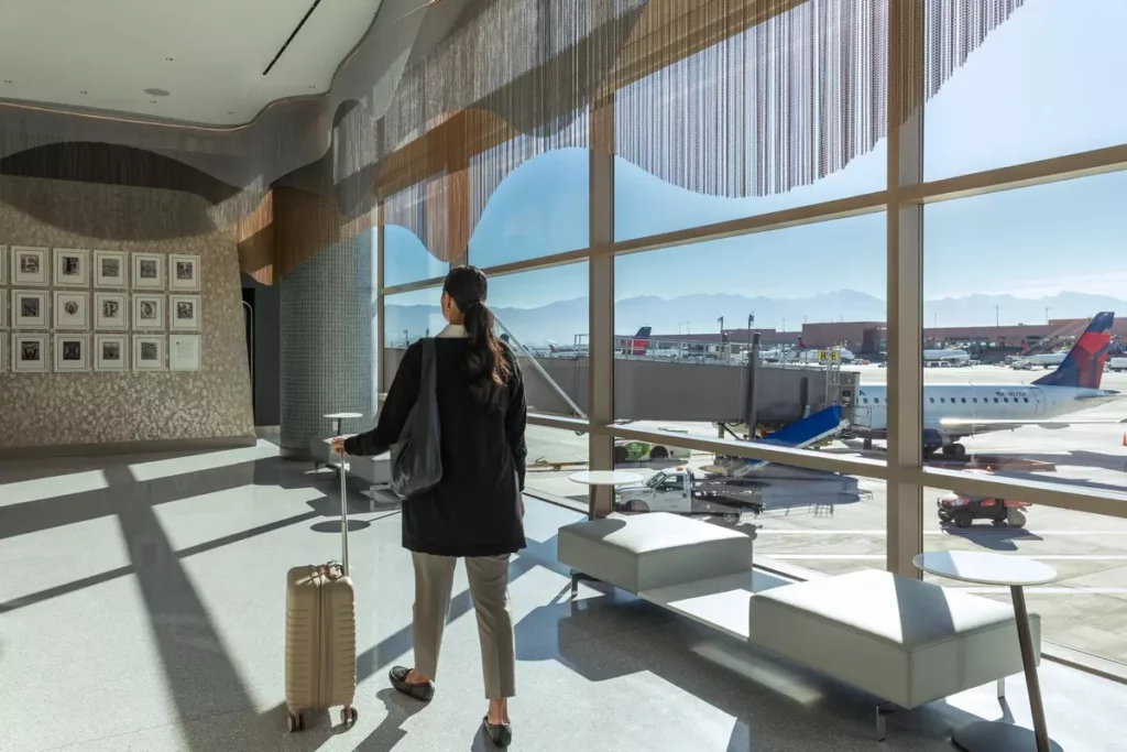 旅客從達美飛凡貴賓室（Delta Sky Club）俯瞰鹽湖城國際機場跑道，窗外可見壯麗山景與達美航空機隊