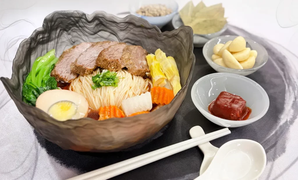 台北二館推出「深石坪四天三夜逍遙遊」雙人每房9,999元,除了升等豪華客房、動物園與貓纜門票外,再贈甫獲2025臺北國際牛肉麵節鮮食創意銀獎的雙人蒜香腐乳牛肉麵