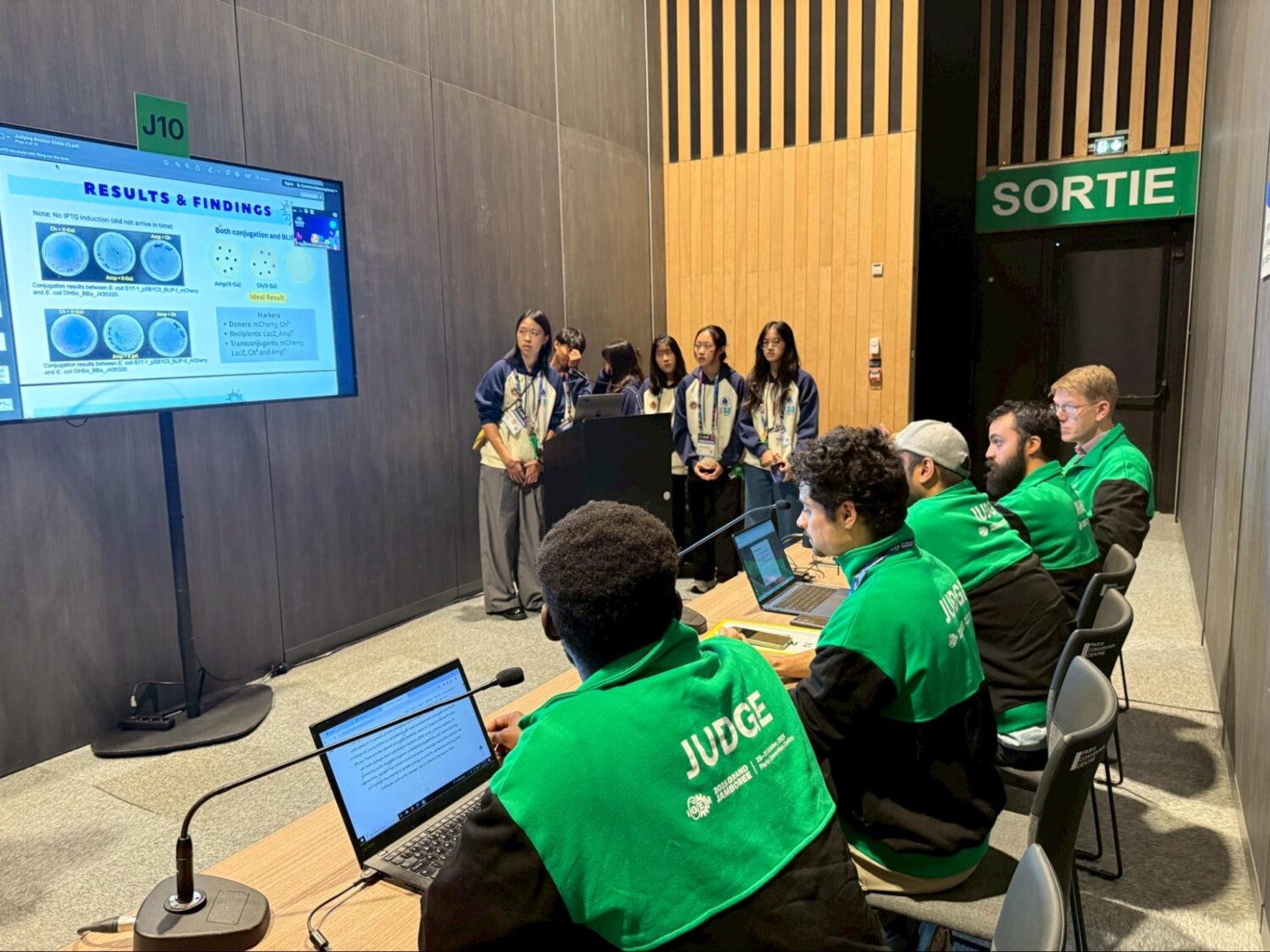 HIA-Taiwan PlasMission 團隊於 iGEM Grand Jamboree 現場向國際評審進行研究簡報,展現自主實驗成果與合成生物學應用構想。(圖/記者張家燁翻攝)