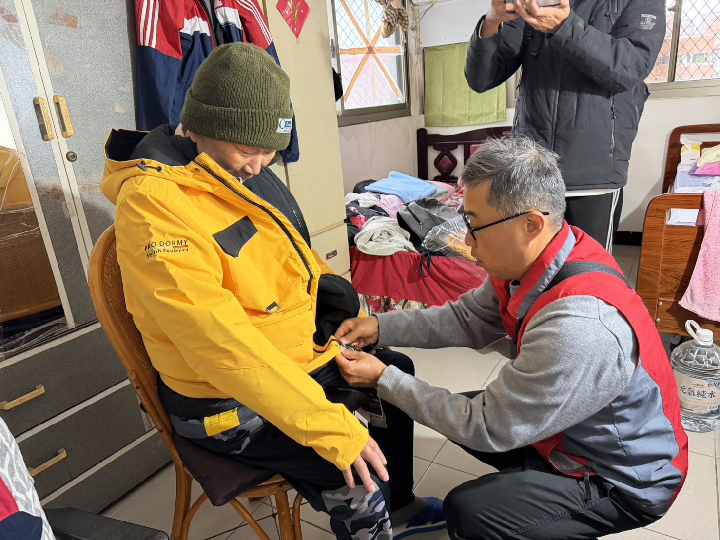 關懷五股區高齡榮民 新北榮服處寒天送暖到府 23 《圖說》李毓錫副處長貼心協助毛伯伯試穿保暖外套,並仔細調整尺寸。〈新北榮服處提供〉