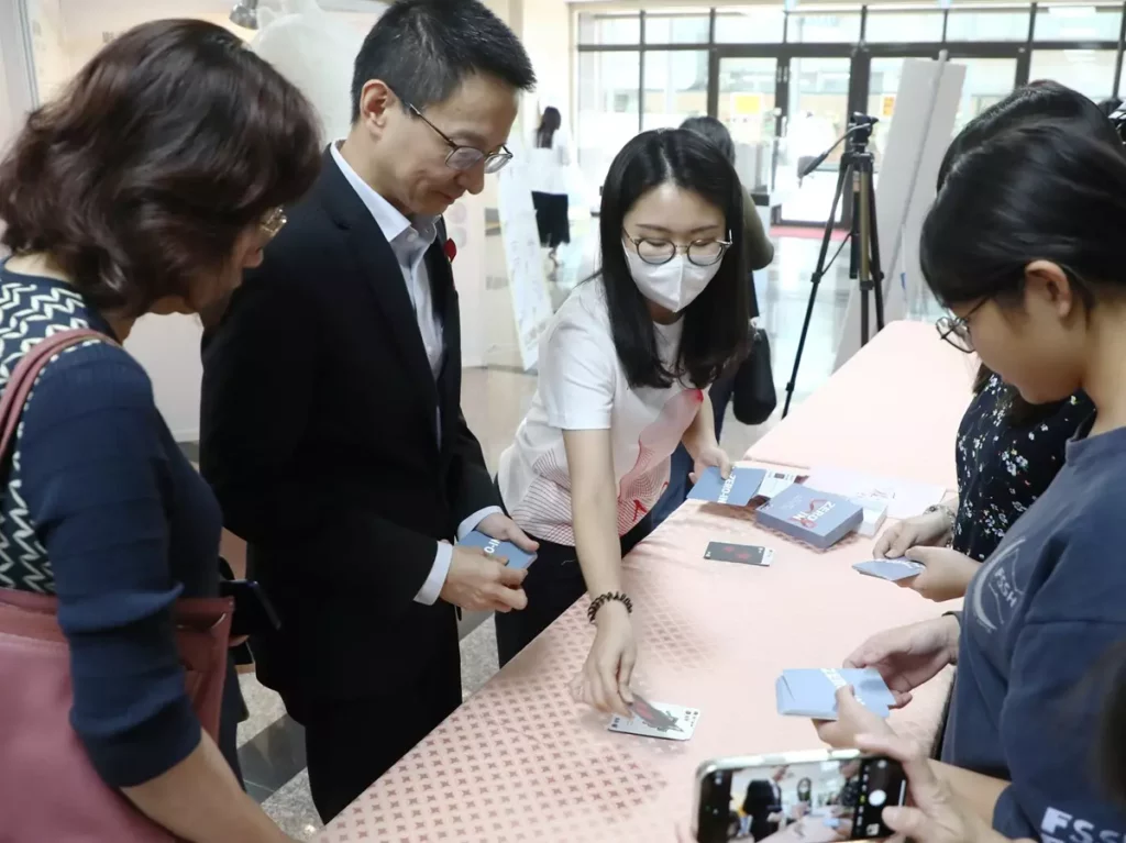 衛福部疾管署長羅一鈞(左二)和學生一起玩HIV生存戰卡牌。(圖/中山醫大提供)