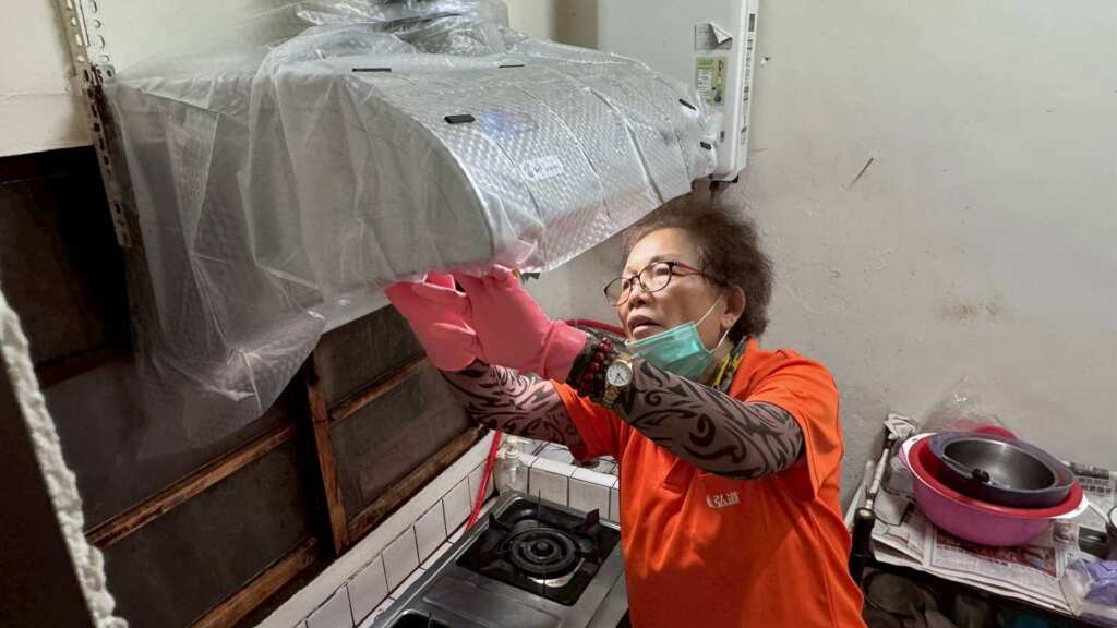 ▲弘道志工替阿喜阿嬤家的抽油煙機更換上新的防塵罩。（圖／弘道老人福利基金會提供）