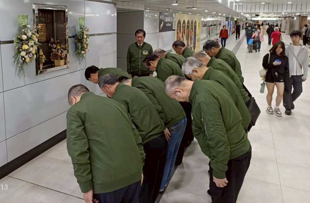 一群花甲老翁向台北車站憲兵義士楊榮華紀念牌鞠躬,獻花致敬。 (憲兵校友會提供)