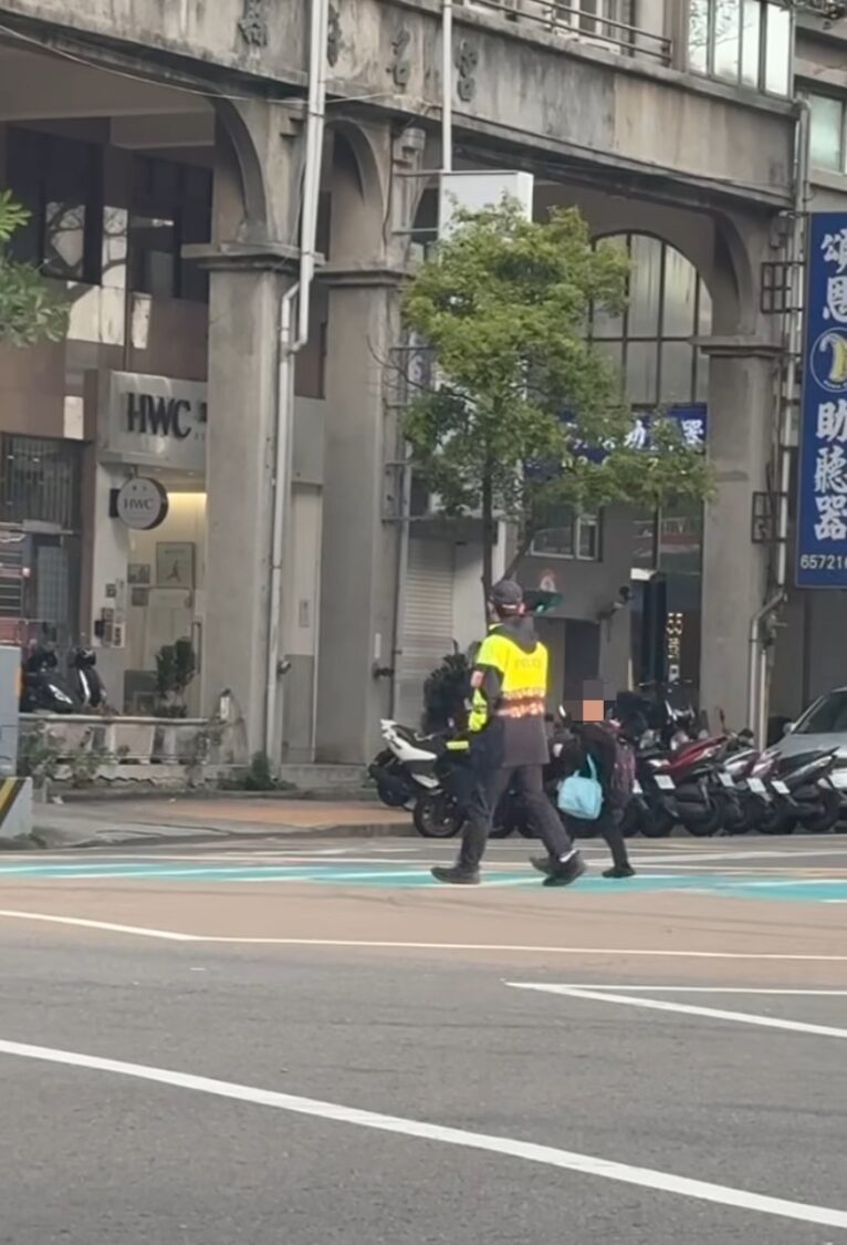 上學尖峰時段車流繁忙,新竹縣政府警察局竹北分局員警於路口陪伴學童通行,以身體作為防線,確保孩子安全過馬路,守護通學安全。(圖/記者張家燁翻攝)