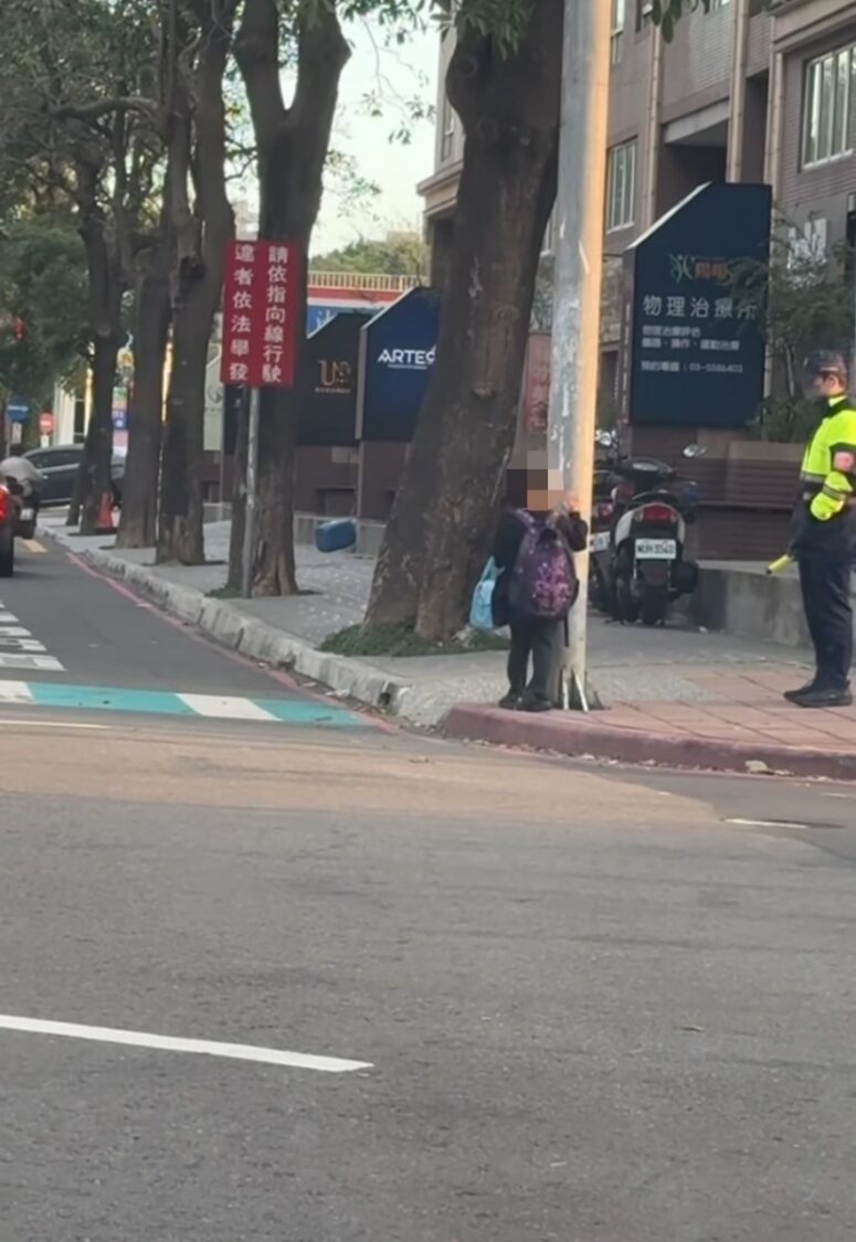學童安全抵達路口等待區,員警持續在旁警戒來車動向,細心留意行人通行狀況,展現警察日常交通勤務中的暖心守護。(圖/記者張家燁翻攝)