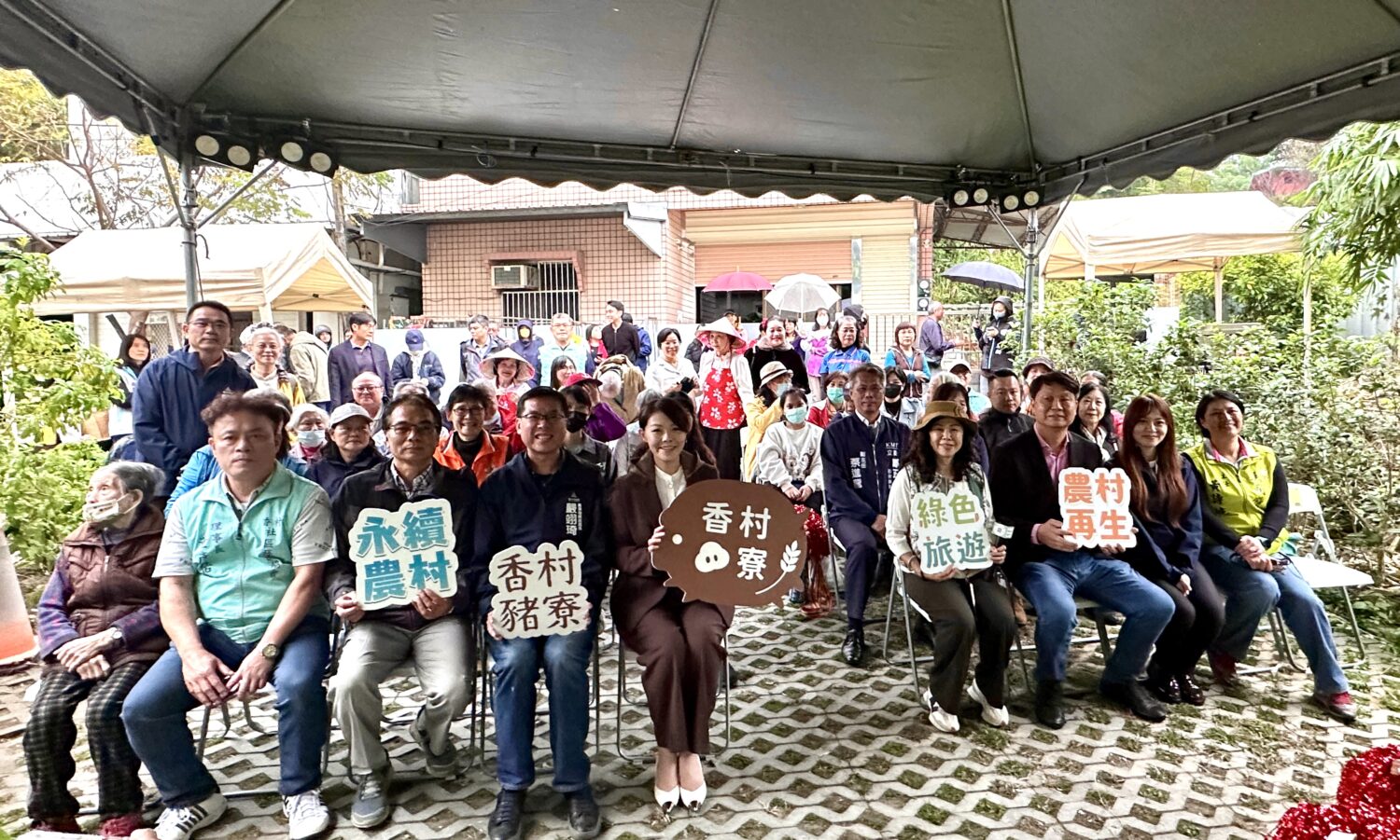 香村豬寮啟用活動吸引大批社區居民到場參與,高虹安市長與市府團隊、社區夥伴一同手持「永續農村」、「綠色旅遊」、「農村再生」標語合影,展現香村推動永續發展的共同願景。(圖/記者林照東攝)