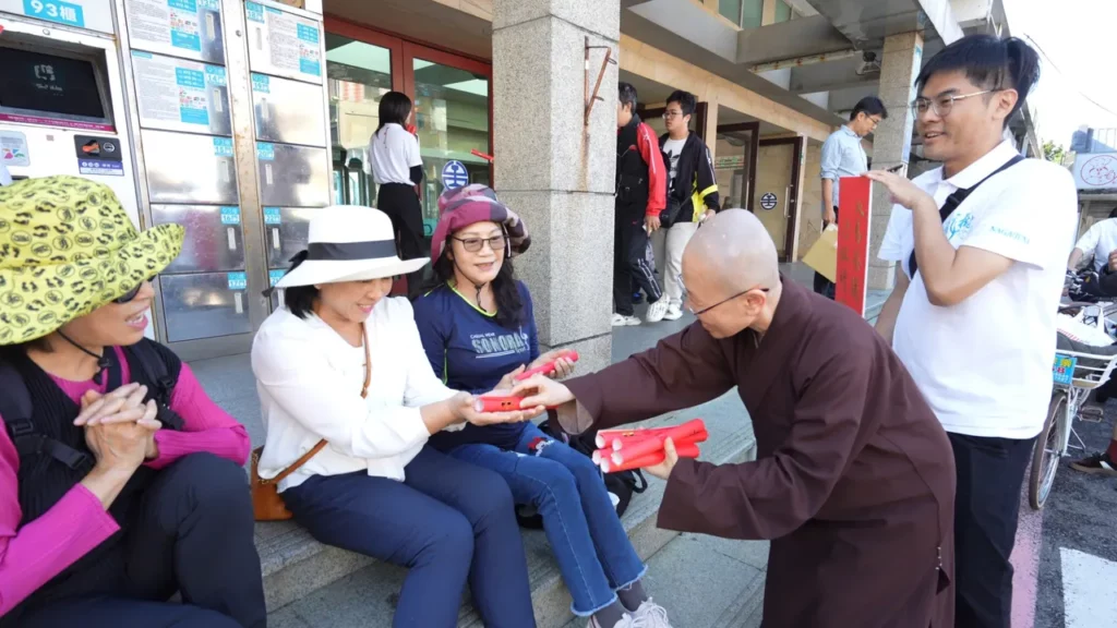 靈鷲山法師在福隆火車站前發春聯給民眾。(圖由靈鷲山佛教教團提供)