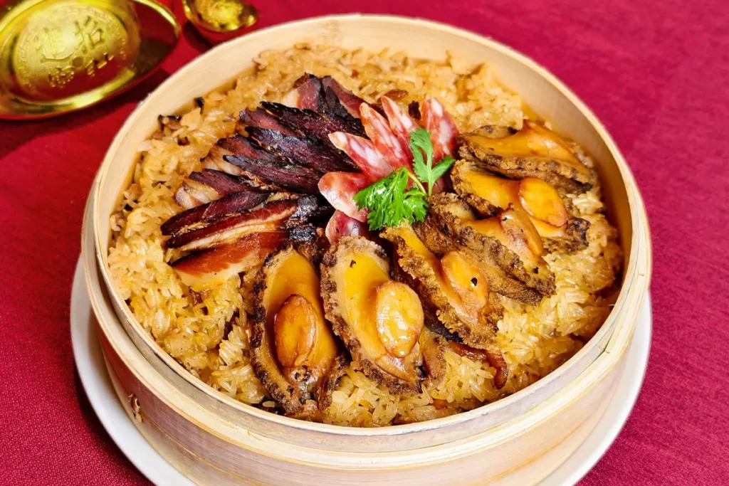 凱華樓年菜「老廣臘味九孔鮑魚飯」堆疊油飯、臘味與九孔鮑魚的三重香氣。