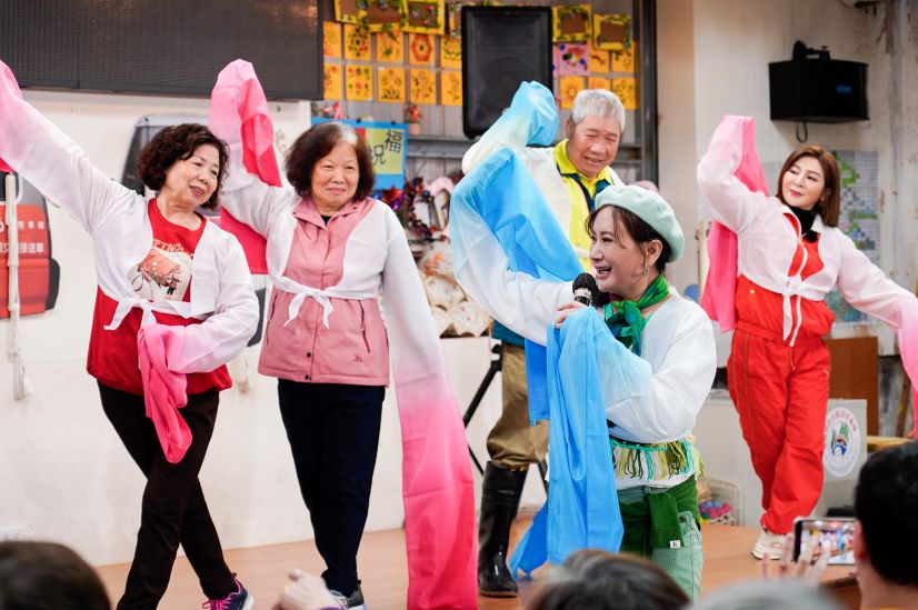 娛樂牡丹心據點長輩 〈台灣優質生命〉獻藝又送暖 38 《圖說》知名歌仔戲演員陳亞蘭教長輩舞動水袖,台上右1為王彩樺 右2為牡丹心社區協會理事長陳專森。〈社會局提供〉