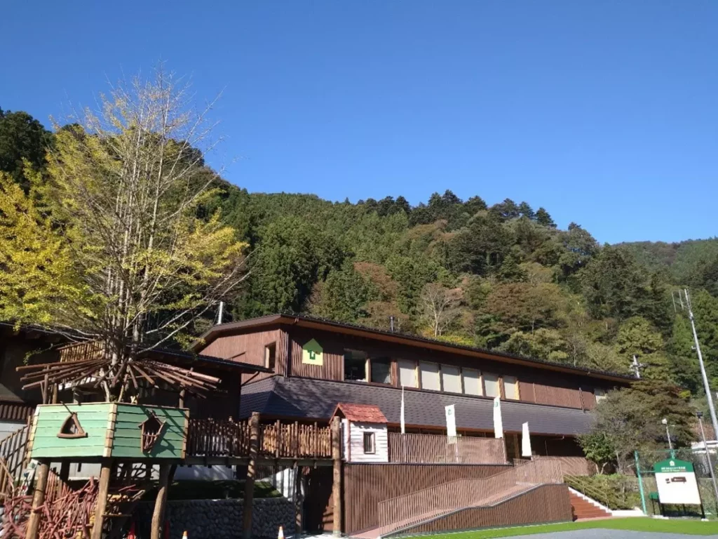 檜原森之玩具美術館的木造建築,坐落於綠意盎然的山林之中,與周邊自然環境融為一體,展現溫暖而親近自然的氛圍。©檜原森のおもちゃ美術館