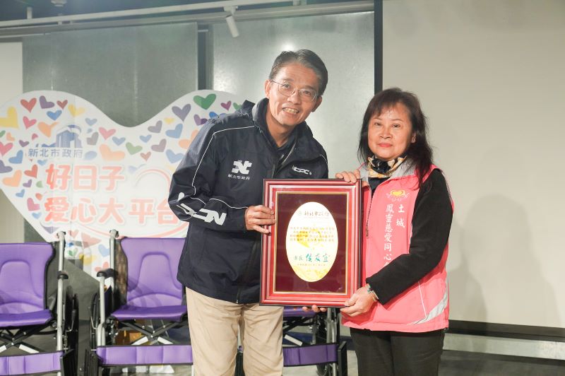 善心企業團體讓愛輪轉 9單位合捐新北305台輪椅 36 《圖說》新北市府秘書長邱敬斌(左)代表侯友宜市長回贈感謝牌給土城鳳靈慈愛同心會理事長黃妙鳳。〈社會局提供〉