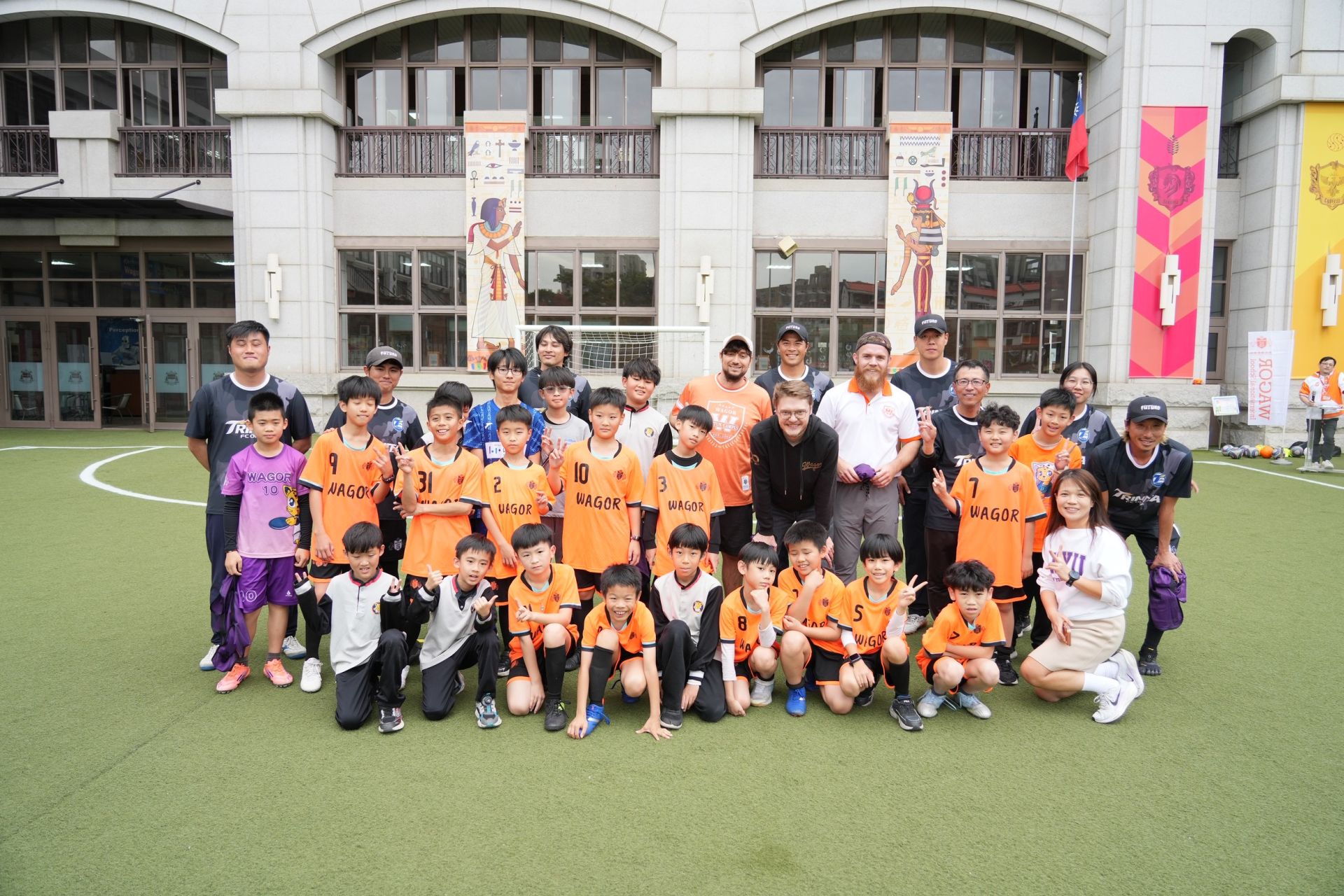 國際足球課程交流現場,學生與教練在校園球場熱血互動,氣氛熱烈。