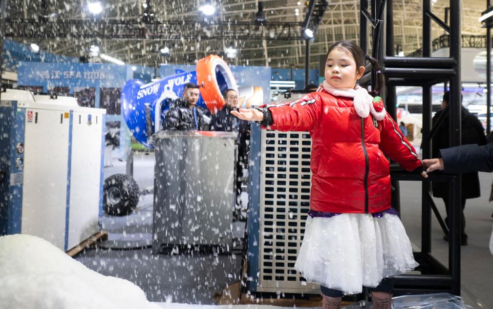 ▲在2026哈爾濱國際冰雪經濟博覽會冰雪裝備展區,小朋友觸摸製雪機現場製造的雪花。
