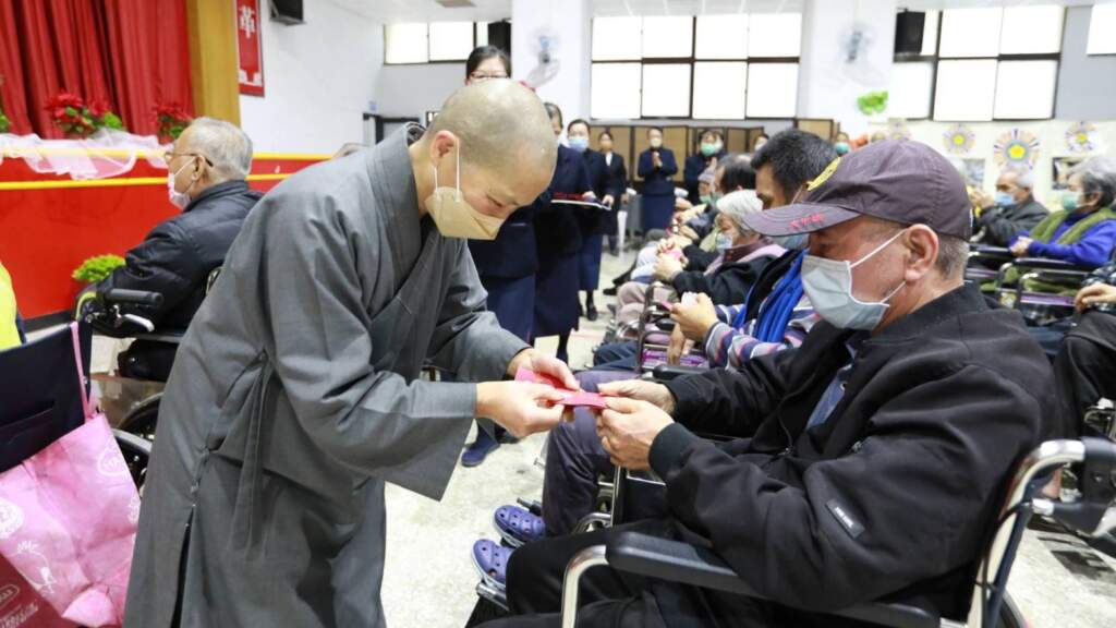 ▲慈濟精舍師父親手逐一發放象徵祝福與智慧的「福慧紅包」,將關懷與溫暖傳遞到每一位長輩手中。(圖/彰化榮家提供)