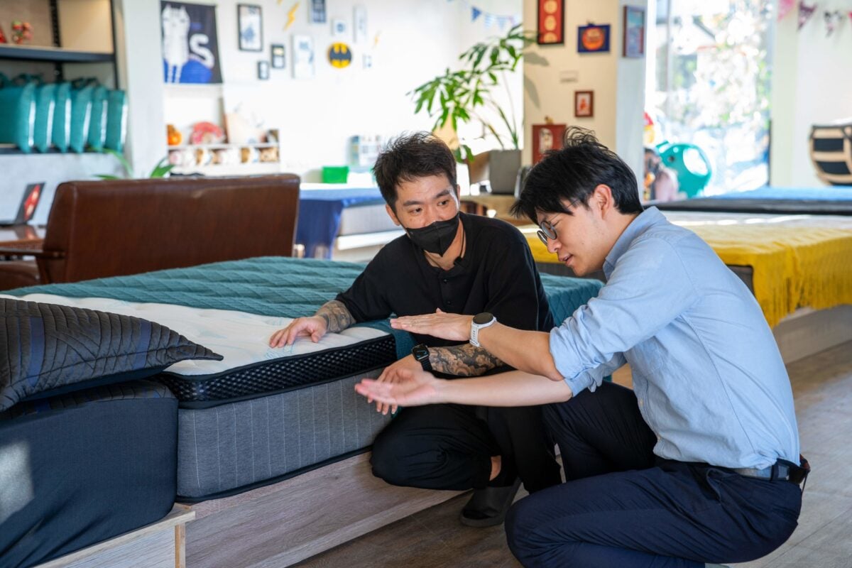 ▲青年局長林楷軒(右)聆聽「春之漾床業」負責人楊明儒(左)介紹床墊結構與材料設計,了解品牌如何透過分層配置提升睡眠支撐度。